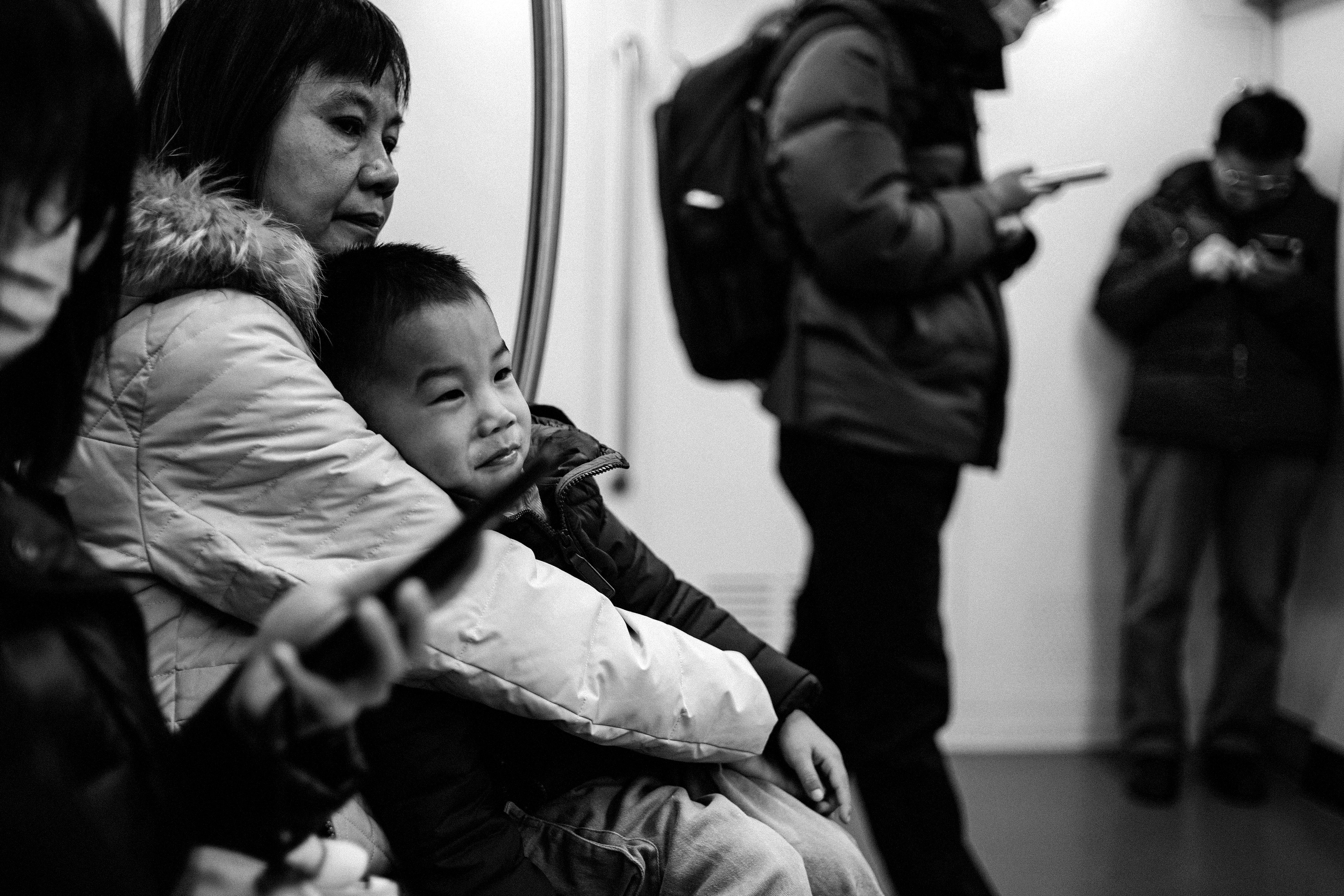 An adult holds a young child close on public transport.